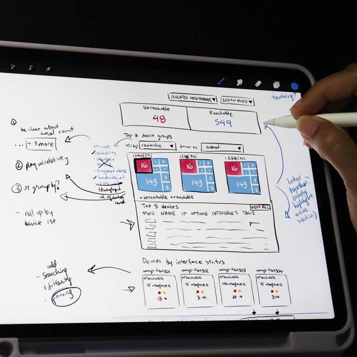 A hand sketching a wireframe on a tablet with a stylus