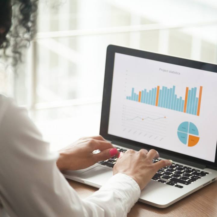 A person typing on a laptop showing charts